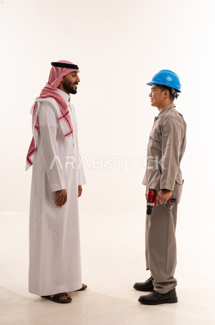 رجل سعودي يتحدث مع عامل آسيوي بمثقاب كهربائي