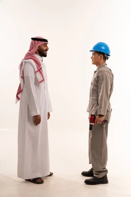 رجل سعودي يتحدث مع عامل آسيوي بمثقاب كهربائي