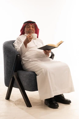 Elderly Saudi Man Reading Book and Drinking Coffee
