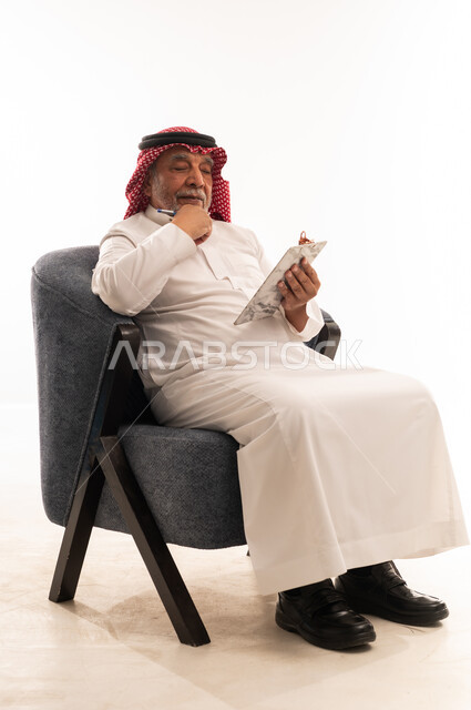 رجل سعودي مسن يكتب على لوحة ملاحظات خلفية بيضاء