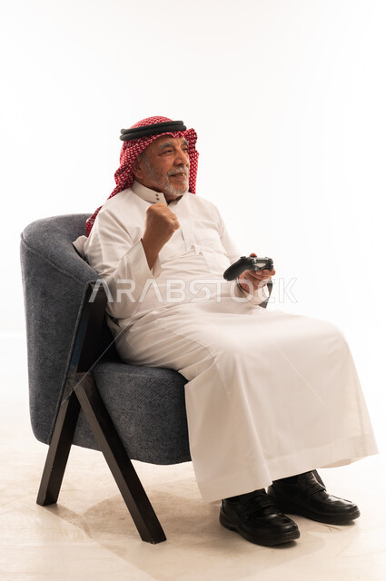 رجل سعودي مسن يلعب ألعاب الفيديو على خلفية بيضاء