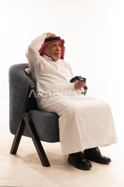 رجل سعودي مسن يلعب ألعاب الفيديو بخلفية بيضاء