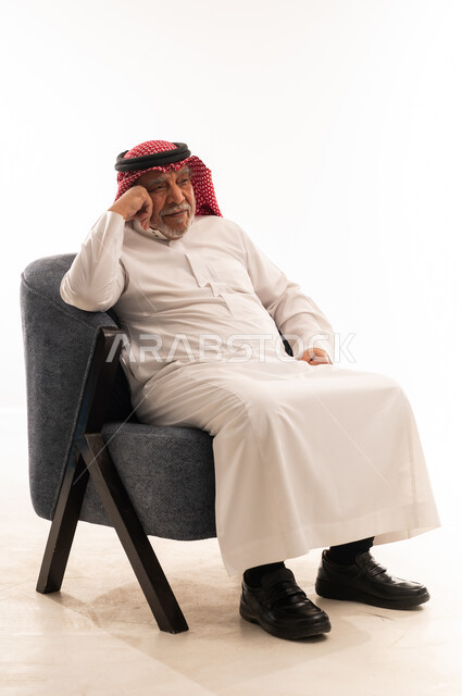 رجل سعودي مسن بالثوب التقليدي يجلس على كرسي