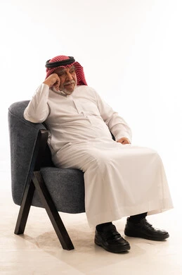 Elderly Saudi Man in Traditional Thobe Sitting in Armchair