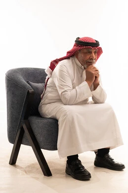 رجل سعودي مسن يجلس على كرسي في استوديو