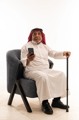رجل سعودي مسن مع هاتف ذكي وعصا في الاستوديو