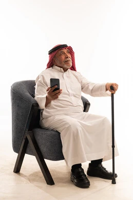 رجل سعودي مسن مع هاتف ذكي وعصا مشي