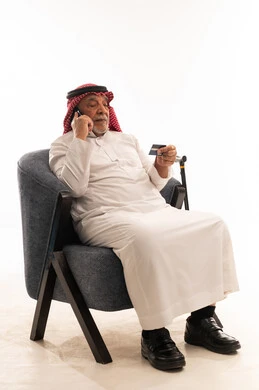 Elderly Saudi Man Using Credit Card on Mobile Phone