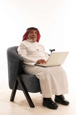رجل سعودي مسن يستخدم المحمول على كرسي أزرق