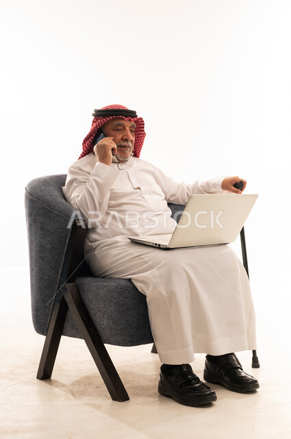 رجل سعودي مسن يستخدم اللابتوب والجوال