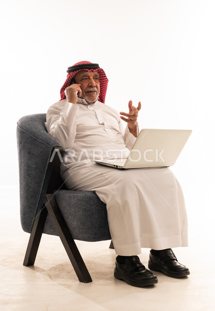 رجل سعودي مسن مع لابتوب وهاتف ذكي