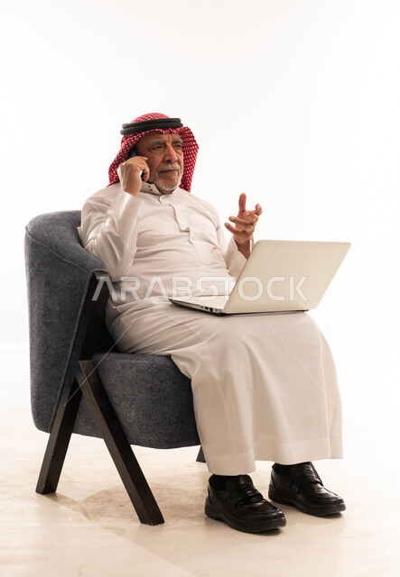 رجل سعودي مسن مع لابتوب وهاتف محمول