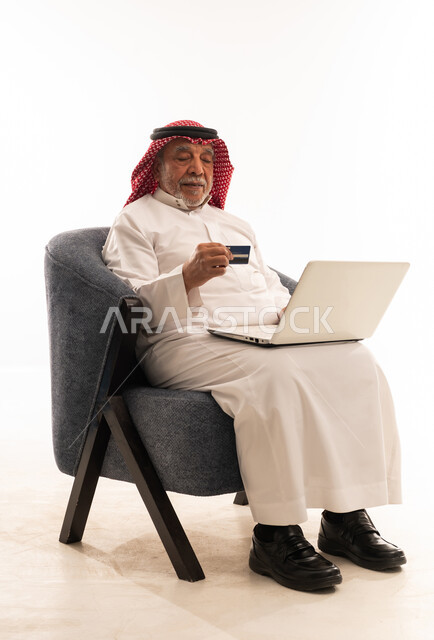 رجل سعودي مسن يستخدم اللابتوب وبطاقة الائتمان