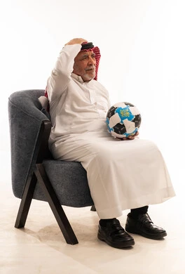 رجل سعودي مسن يحمل كرة قدم بخيبة أمل