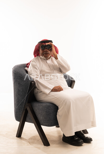 رجل سعودي يرتدي الزي التقليدي ويستخدم المنظار