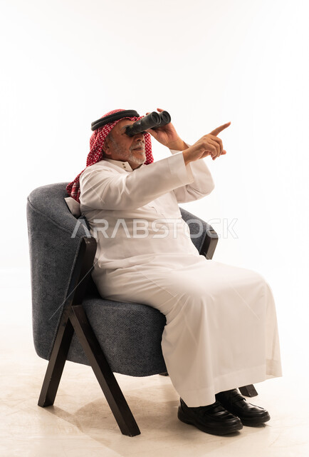 رجل سعودي مسن يستخدم المنظار على خلفية بيضاء