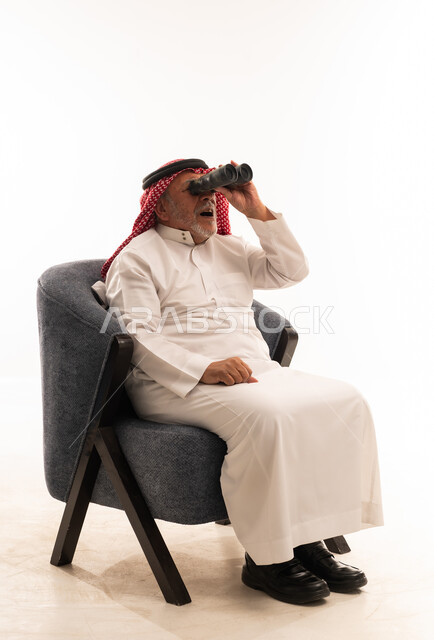رجل سعودي مسن بالزي التقليدي يستخدم المنظار