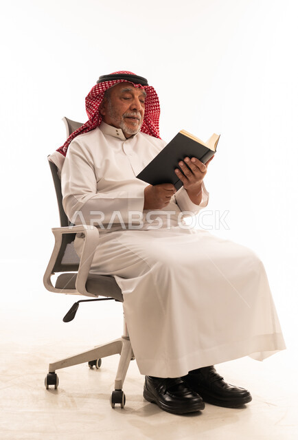رجل سعودي مسن يقرأ كتاباً على خلفية بيضاء