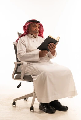 رجل سعودي مسن يقرأ كتاباً على خلفية بيضاء