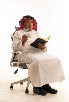 Elderly Saudi Man Reading Book with Coffee