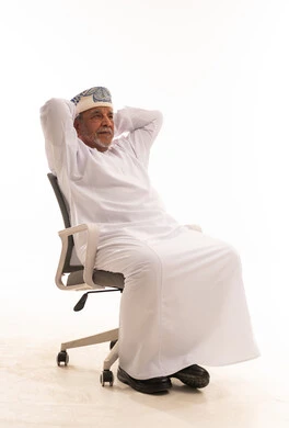 رجل عماني مسن بالزي التقليدي يجلس بوضعية مريحة