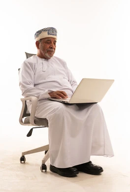 Elderly Omani Man Working on Laptop in Office Chair