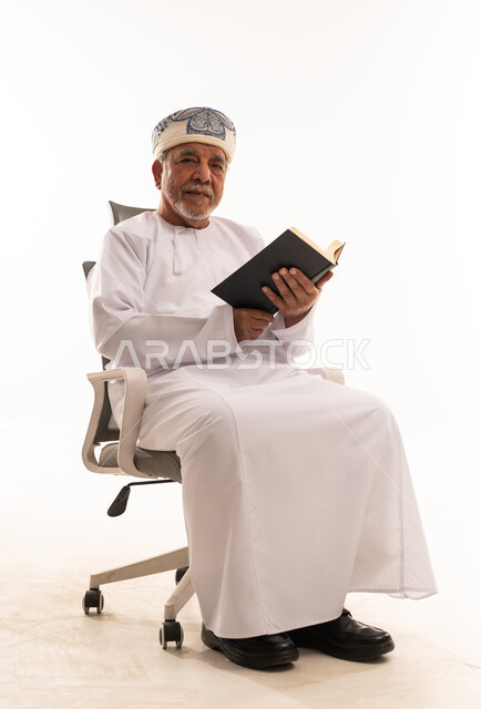 Elderly Omani Man in Traditional Dress Reading Book