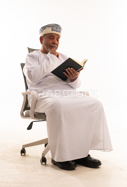 رجل عماني مسن بالزي التقليدي يقرأ كتاباً