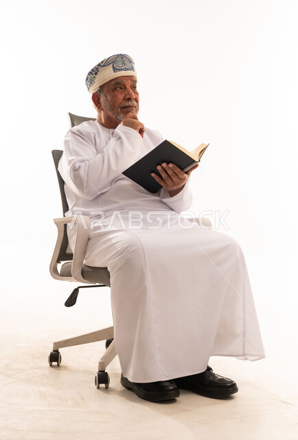 Elderly Omani Man in Traditional Dress Reading Book