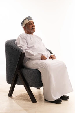 رجل عماني مسن بالزي التقليدي يجلس على كرسي