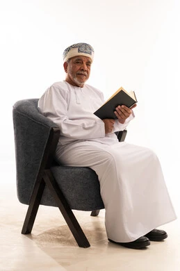 Elderly Omani Man Reading Book in White Studio