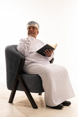 رجل عُماني مسن بالزي التقليدي يقرأ كتاباً