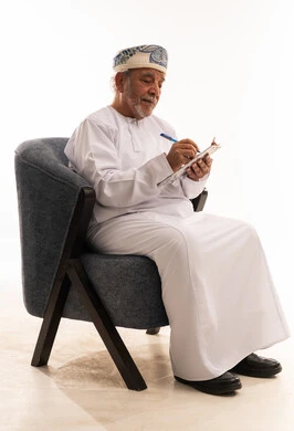 رجل عماني بالزي التقليدي يكتب على لوحة ملاحظات