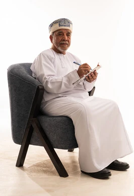 رجل عُماني مسن يحمل لوحة كتابة في استوديو