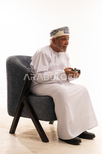 رجل عماني مسن يلعب ألعاب الفيديو في الاستوديو