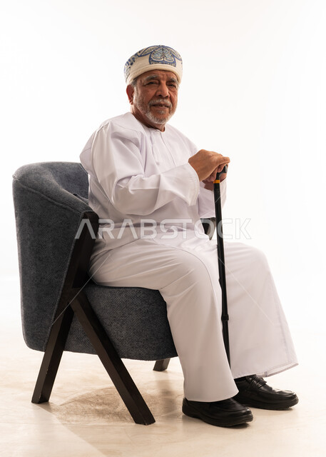 رجل عماني مسن بالزي التقليدي مع عصا المشي