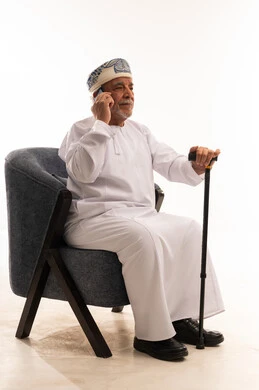 Elderly Omani Man with Walking Stick on Mobile Phone