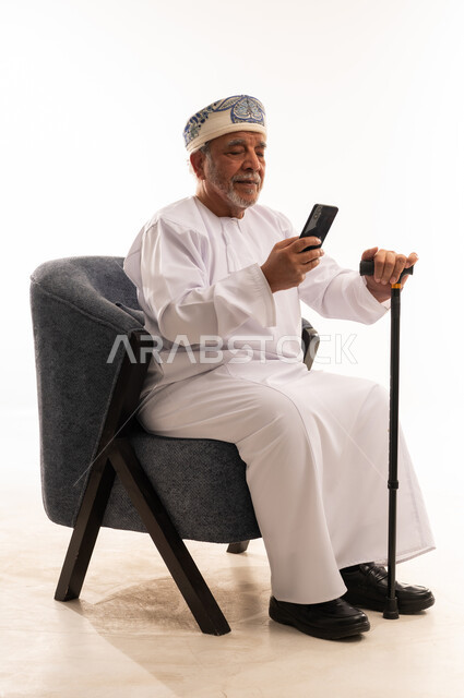 Elderly Omani Man with Smartphone and Walking Stick