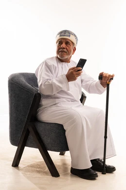 رجل عماني مسن يحمل هاتف ذكي في الاستوديو