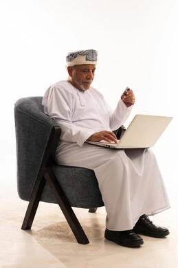 Omani Senior Using Laptop and Credit Card