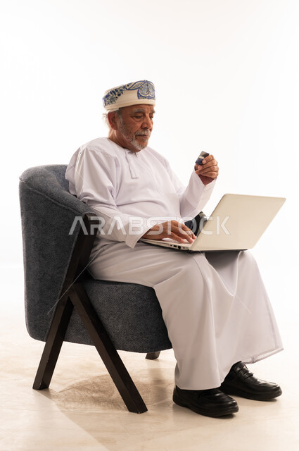 Omani Man Using Laptop and Credit Card