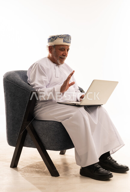 Elderly Omani Man in Traditional Dress Using Laptop