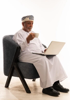 Omani Man in Traditional Dress Using Laptop