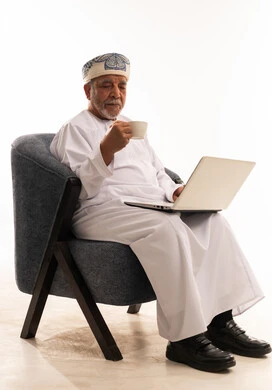 Omani Senior Man Using Laptop with Coffee Cup
