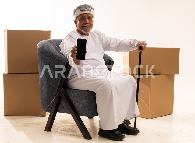 رجل عماني مسن مع هاتف ذكي وصناديق شحن
