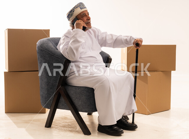 Elderly Omani Man on Phone with Moving Boxes