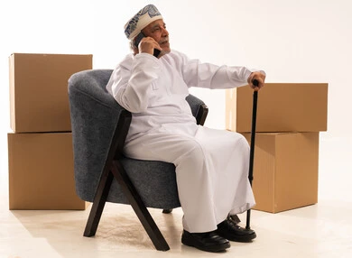 Elderly Omani Man on Phone with Moving Boxes