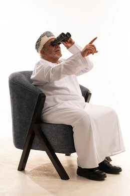 رجل عماني مسن بالزي التقليدي يستخدم المنظار