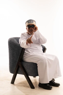 Senior Omani Man with Binoculars Sitting in Armchair
