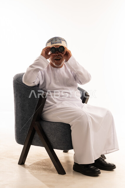 رجل عماني بالزي التقليدي يستخدم المنظار في الاستوديو